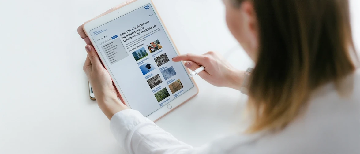A person uses a tablet and stylus to browse a clean, modern website, pointing at image thumbnails and information in a bright, minimal workspace.